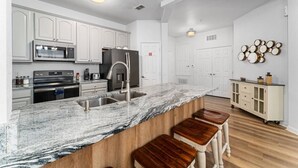 A modern kitchen with white cabinetry, a marble countertop, a stainless steel sink, and a built-in oven. - Vista Cay 3BR Near Universal & Convention (Orlando)
