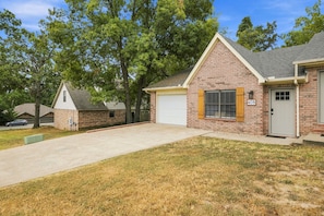 A residential property with a brick exterior, a garage, and a well-maintained lawn. - Switchback Suites - Side B (Bentonville)