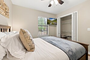 Ein Schlafzimmer mit Bett, Fenster mit Blick, Deckenventilator und Kleiderschrank.