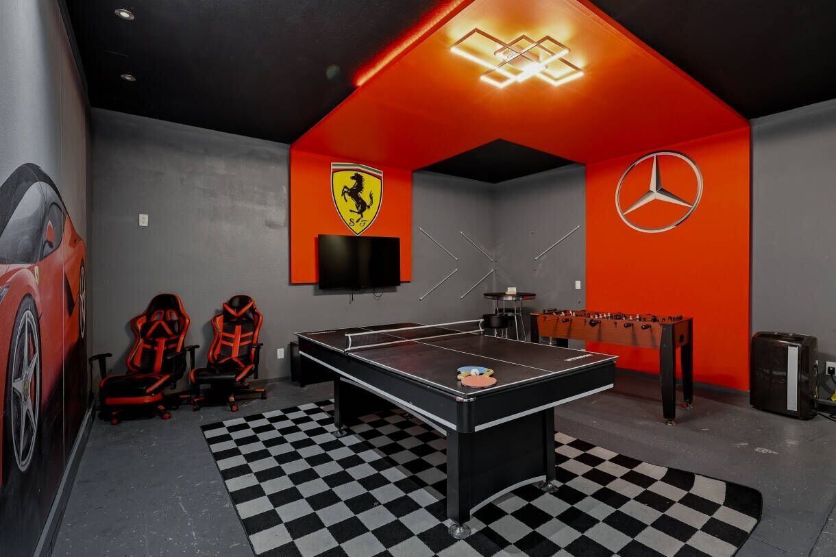 A room with a foosball table, two gaming chairs, a table tennis table, and a checkered floor.