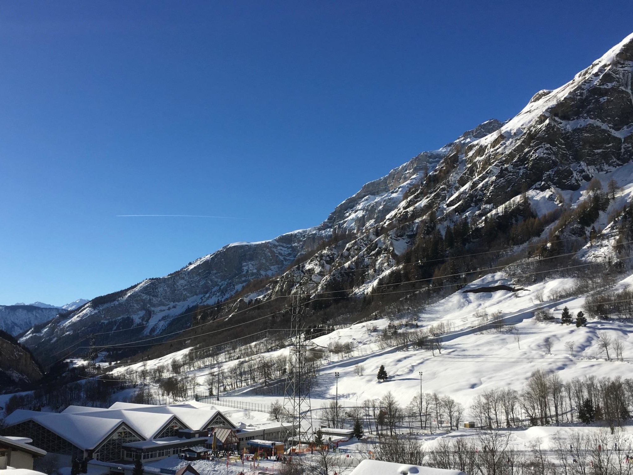 Paisatge de muntanya amb vessants nevades i una estació d'esquí en primer pla.