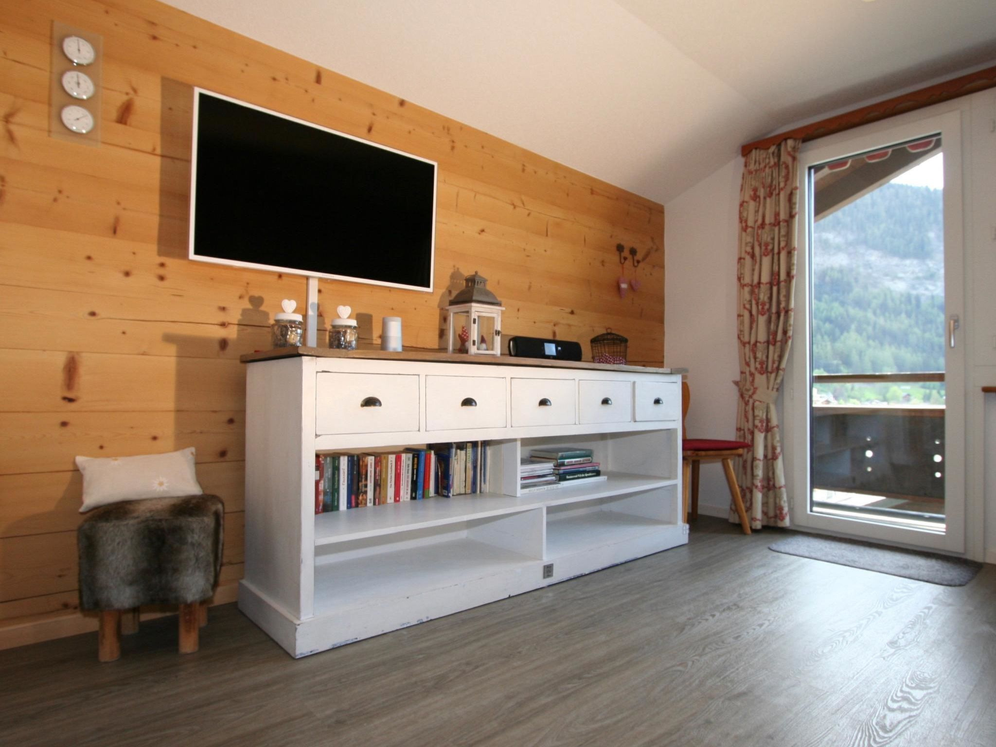 Ein Zimmer mit einem weißen Schrank, einem Flachbildfernseher und einem Bücherregal.