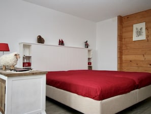 Ein Schlafzimmer mit einem Bett, einem Schreibtisch und Regalen mit diversen Gegenständen.