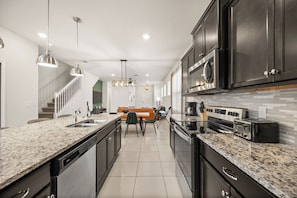 A modern kitchen with granite countertops, stainless steel appliances, and dark cabinetry. - 4039-Lana (Davenport)
