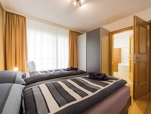Ein Hotelzimmer mit zwei Betten, einem Badezimmer und einer Tür zu einem weiteren Raum.