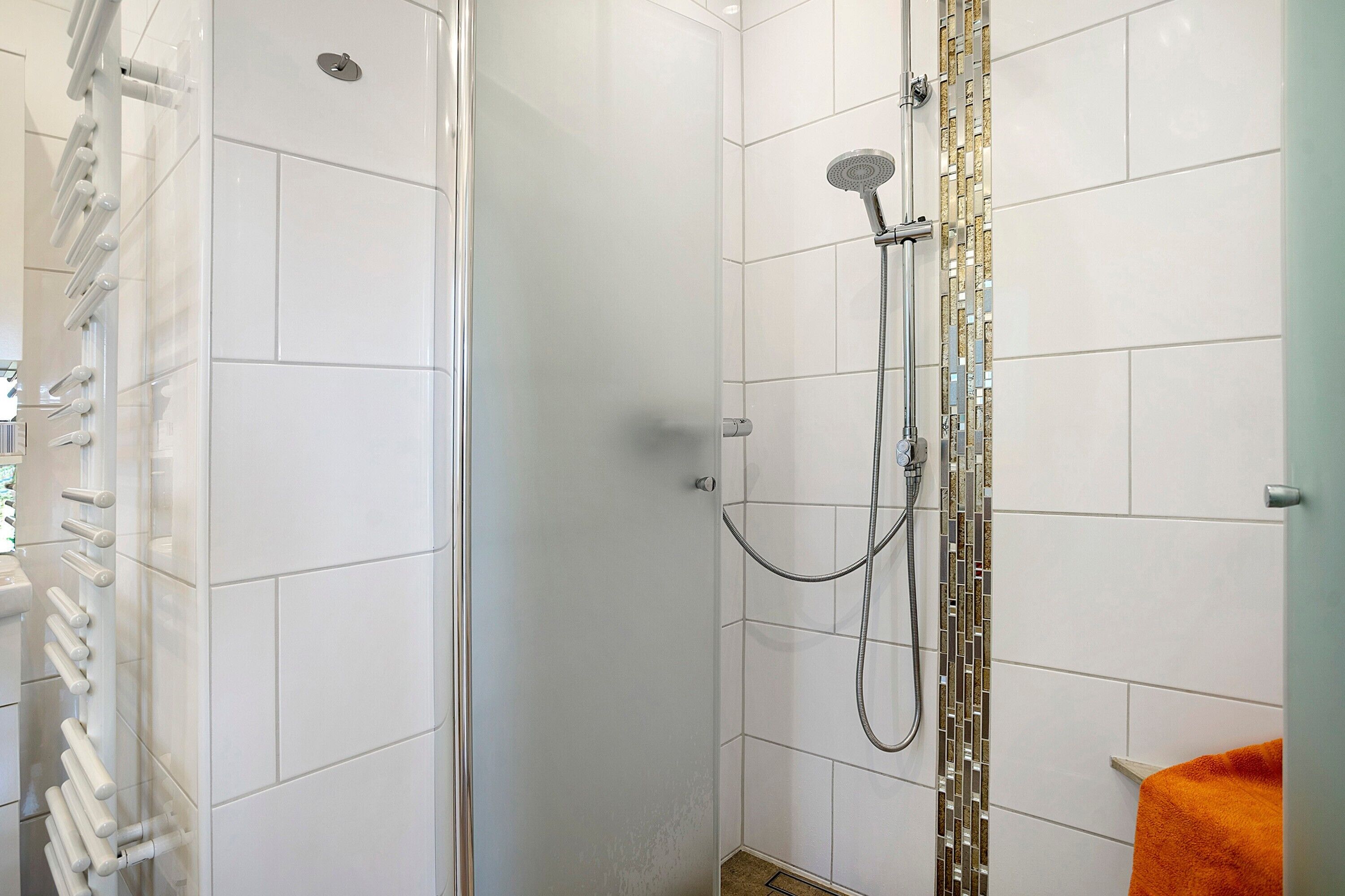 A shower area with a glass door, a showerhead, and a handheld shower attachment.