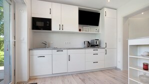 A modern kitchen with white cabinets, a microwave, a coffee maker, and a built-in oven. - Apartment 'Villa Wiese  Vineta' with Wi-Fi (Katzow)