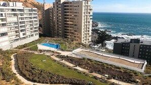Una zona residencial costera con edificios altos, una piscina y un parque ajardinado.