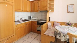 Una cocina compacta con armarios de madera, horno empotrado y una zona de comedor con banco.