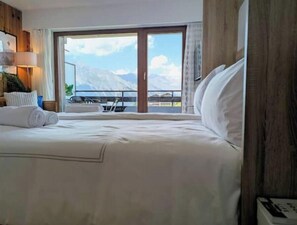 Ein Hotelzimmer mit Bett, Balkon und Bergblick.