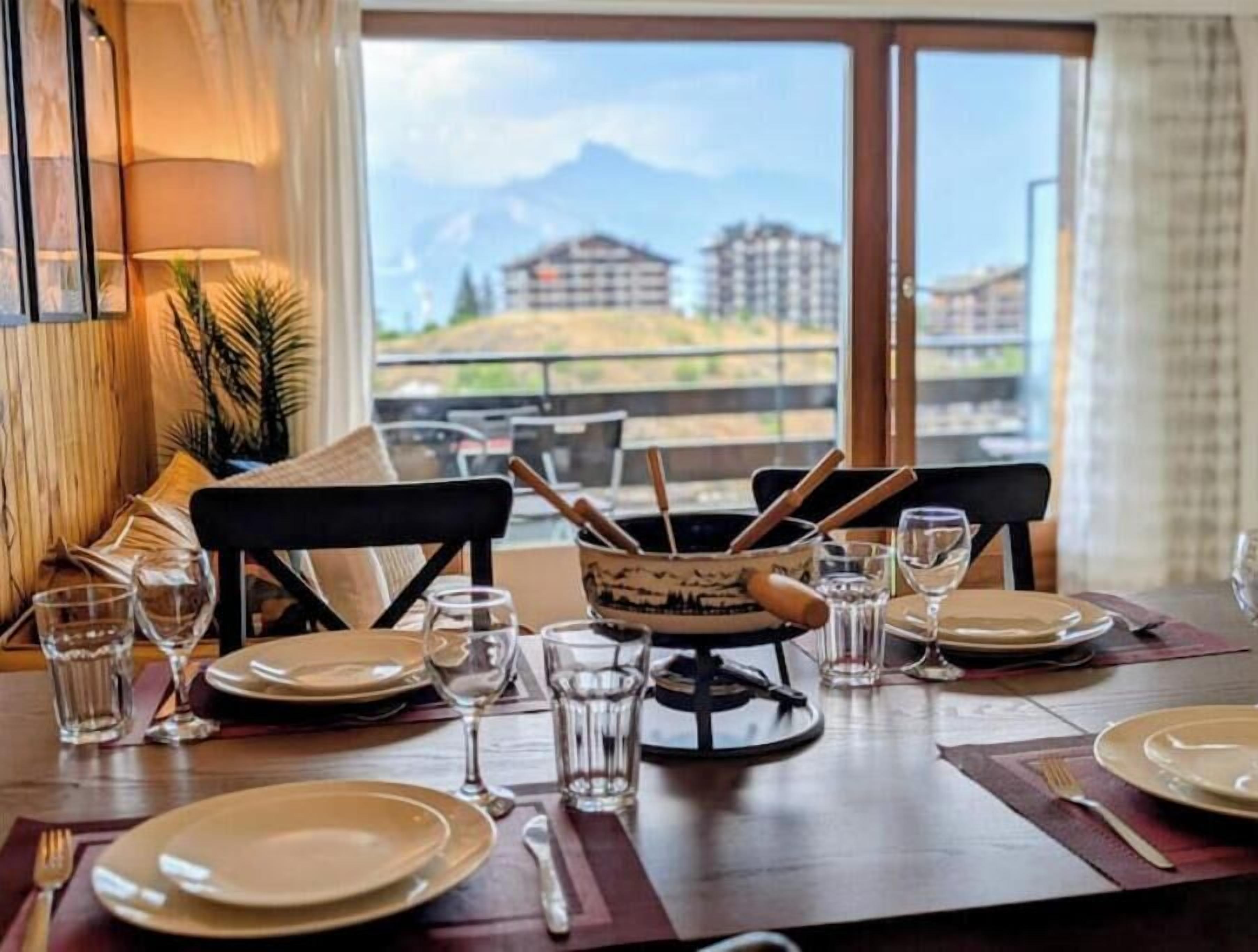 A dining table set for two with a view of buildings and mountains in the background.