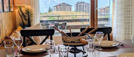 A dining table set for two with a view of buildings and mountains in the background.