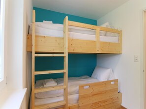 A bunk bed with a wooden ladder, white bedding, and a teal accent wall. - Viktoria B16 by Arosa Holiday Appartement/Fewo, Dusche oder Bad, WC, 4-Bettwohnu by Interhome (Arosa)