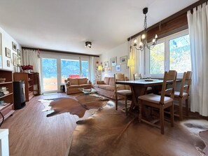 A spacious living area with a large wooden dining table, leather sofa, and a fireplace. - Lärchenwald 1808 # 4-bed apartment, Bad, WC 4-Bettwohnung, Bad, WC by Interhome (Leukerbad)