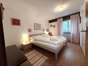 Une chambre à coucher avec un lit, des tables de chevet, une lampe et des tableaux encadrés accrochés au mur.