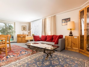 Ein Wohnzimmer mit einer Couch, einem Couchtisch, einem Teppich mit Muster, einer Kommode und einer Lampe.