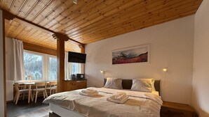 Una camera da letto con un letto grande, una scrivania con sedie, un televisore e un quadro appeso al muro.