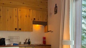 Una cucina funzionale con mobili in legno, un piano di lavoro bianco, un tavolo con sedie e una finestra con tende.