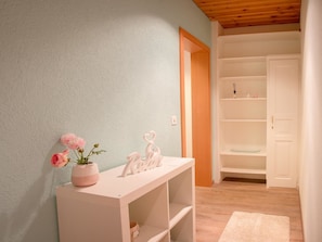 A room with a white console table, a pink vase with flowers, and a white door leading to a closet with shelves. - Miraflor Sonja by Arosa Holiday Appartement/Fewo, Dusche und Bad, WC, 2-Bettwohn by Interhome (Arosa)