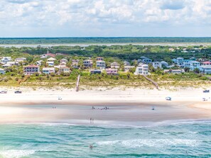 Eine Küstenlandschaft mit Strandhäusern, einem Sandstrand und dem Meer.