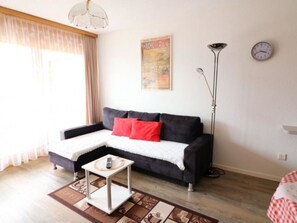 Ein Wohnzimmer mit Sofa, Couchtisch, Stehlampe und Wanduhr.