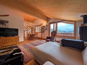A hotel room with a bed, a television, a dining area, and a view of mountains. - Furkasunna by Arosa Holiday Appartement/Fewo, Dusche oder Bad, WC, 7-Bettwohnung by Interhome (Arosa)