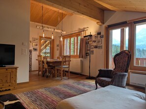 A cozy room with a bed, a TV, a dining area with chairs, a large window with a view, and a wooden ceiling. - Furkasunna by Arosa Holiday Appartement/Fewo, Dusche oder Bad, WC, 7-Bettwohnung by Interhome (Arosa)