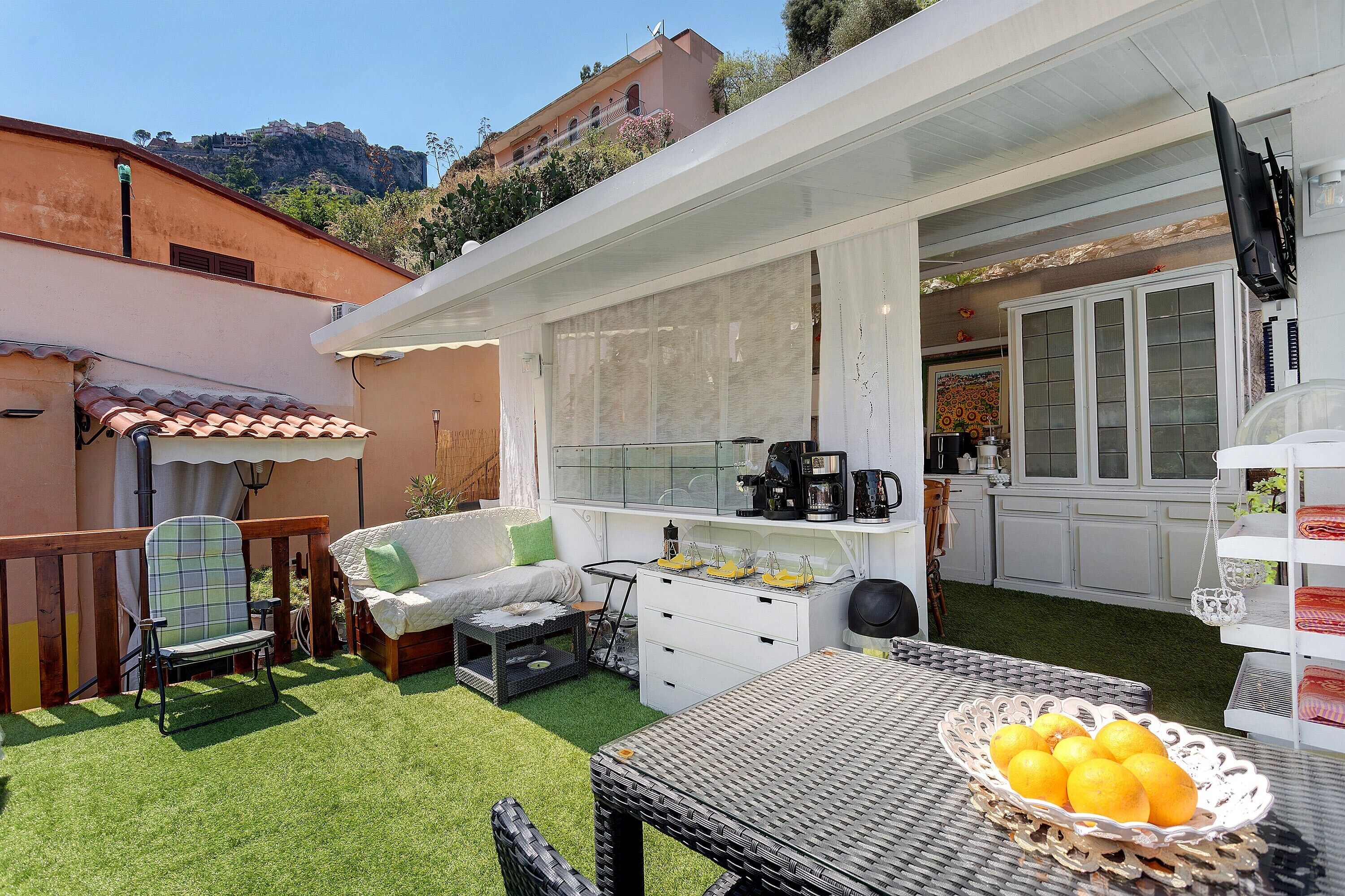 A patio with a table, chairs, and a basket of lemons.