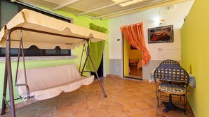 A room with a swing bed, a chair, a table, and a painting on the wall. - Apartment 'Le Grand Soleil - Elios' with Sea View, Wi-Fi and Air Conditioning (Taormina)