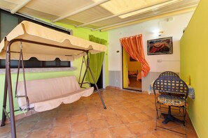 Ein Zimmer mit Hängematte, Stuhl, Tisch und einem Gemälde an der Wand.
