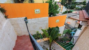 A residential building with a red-tiled roof, orange walls, and a balcony with potted plants. - Apartment 'Le Grand Soleil - Elios' with Sea View, Wi-Fi and Air Conditioning (Taormina)