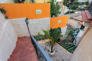 Ein Wohngebäude mit rotem Ziegeldach, orangenen Wänden und einem Balkon mit Blumentöpfen.