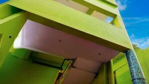 A building with a green facade, a pink lower section, and a clear blue sky in the background. - Hotel O Adamas University Barasat (Barasat)