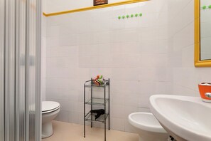 A bathroom with a toilet, a glass shelf with toiletries, and a sink. - Apartment 'Le Grand Soleil - Albatros' with Sea View, Wi-Fi and Air Conditioning (Taormina)