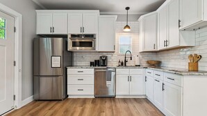A modern kitchen with white cabinetry, stainless steel appliances, and a wooden floor. - Loft Haven Rooftop Terrace (Charlotte)