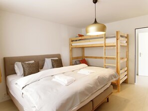 Ein Schlafzimmer mit Etagenbett, Nachttisch, Lampe und Tür.