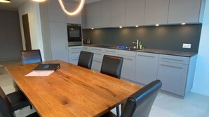A modern kitchen with grey cabinets, a wooden dining table, and black chairs. - Lorez 5D by Arosa Holiday Appartement/Fewo,  , 2-Bettwohnung Lorez 5D by Interhome (Arosa)