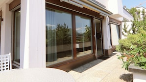 A modern building with large sliding glass doors, a flat roof, and a small garden area with plants. - Lorez 5D by Arosa Holiday Appartement/Fewo,  , 2-Bettwohnung Lorez 5D by Interhome (Arosa)