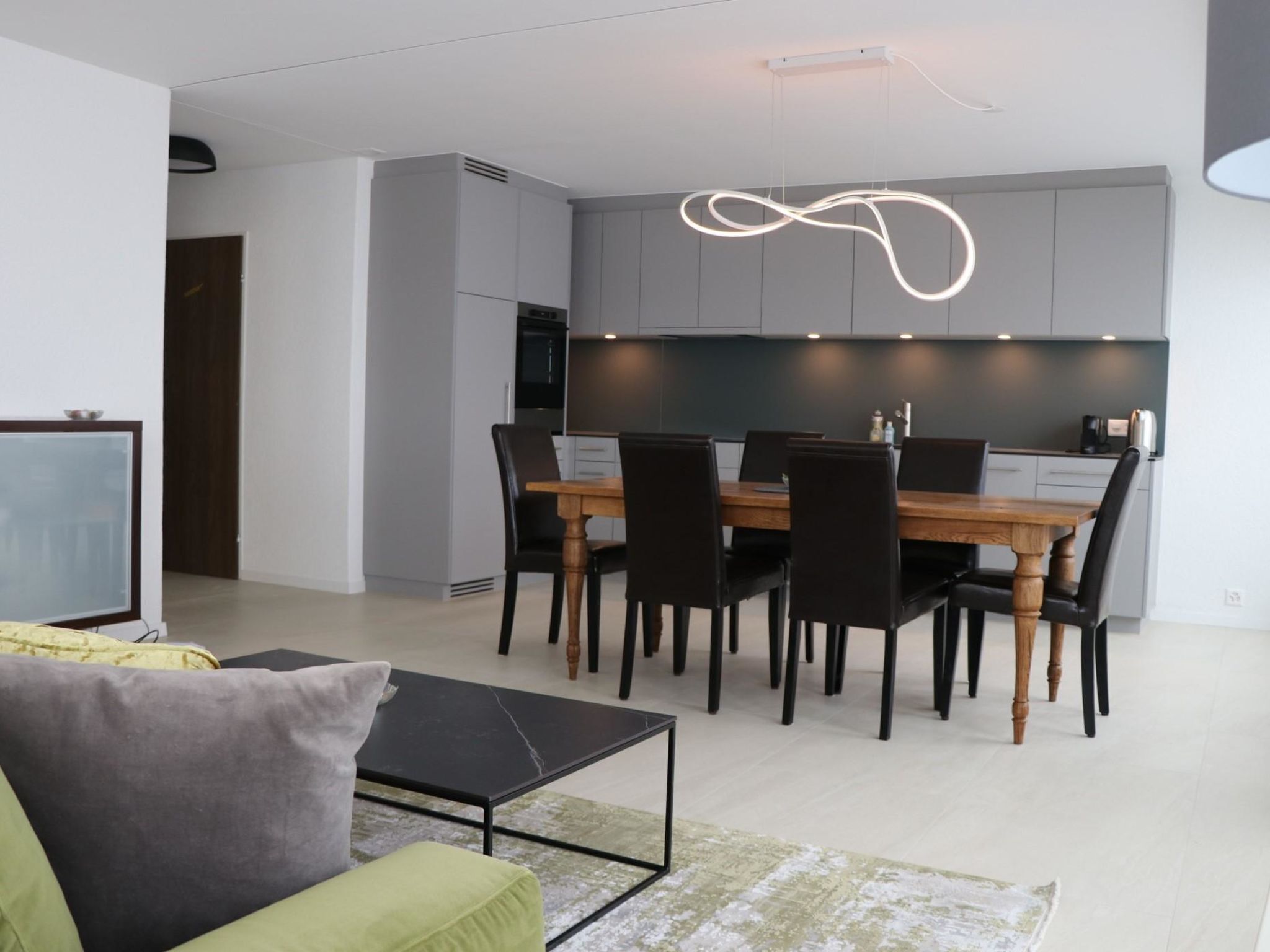 Un salon moderne comprenant un canapé, une table basse et un coin repas avec une table et des chaises.