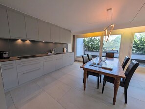 A modern kitchen with grey cabinets, a wooden dining table, and chairs. - Lorez 5D by Arosa Holiday Appartement/Fewo,  , 2-Bettwohnung Lorez 5D by Interhome (Arosa)