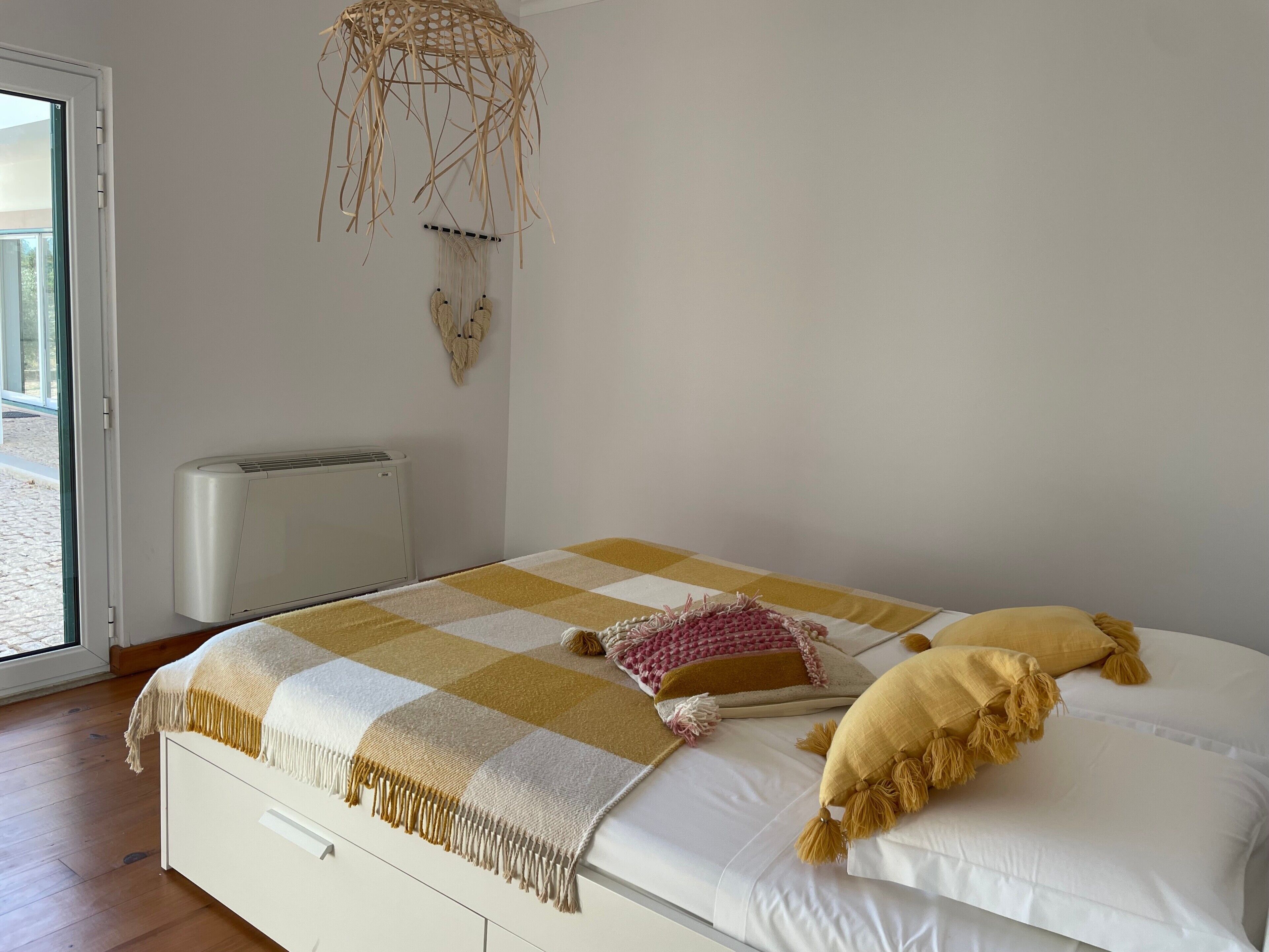 Un dormitorio con cama, aire acondicionado de pared y puerta que da al exterior.