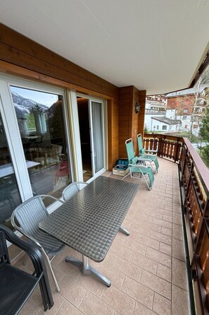 A balcony with a table and chairs, a sliding glass door, and a view of a mountain and buildings. - Edelweiss D 13 # 6-bed apartment, Dusche, WC 6-bed apartment, Dusche, WC by Interhome (Leukerbad)
