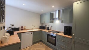 A modern kitchen with a dishwasher, oven, and a built-in stovetop. - Fox House (Llandudno)