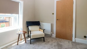 A room with a radiator, a wooden door, and a chair. - Fox House (Llandudno)
