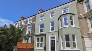 A row of terraced houses with a front entrance, a visible chimney, and a street in front. - Fox House (Llandudno)