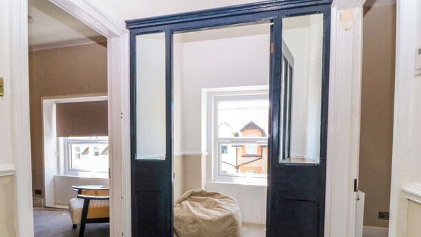 A room with a large window, a bean bag chair, and a door leading to another room. - Fox House (Llandudno)
