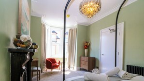 A bedroom with a bed, a chair, a dresser, a desk, and a window with curtains. - Fox House (Llandudno)