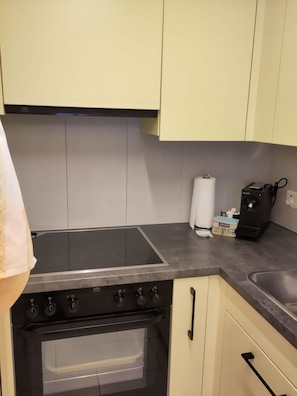 Eine Küche mit einem schwarzen Induktionskochfeld, einem Backofen und einem Spülbecken.