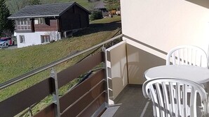 A balcony with a view of a rural landscape, a table with chairs, and a railing. - Valère C 222 # 2-bed apartment, Dusche, WC 2-Bettwohnung, Dusche, WC by Interhome (Leukerbad)