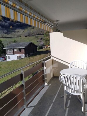 Ein Balkon mit Blick auf eine ländliche Landschaft, ein Tisch mit Stühlen und einem Geländer.